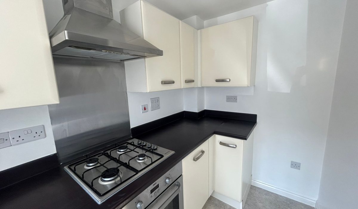 Fitted kitchen with cream units, dark worktops, gas hob and oven