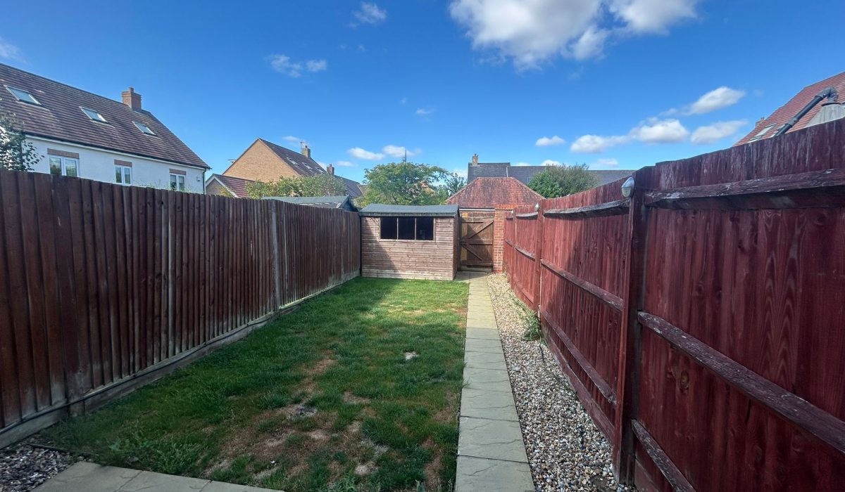 Long enclosed garden with lawn, patio and storage shed